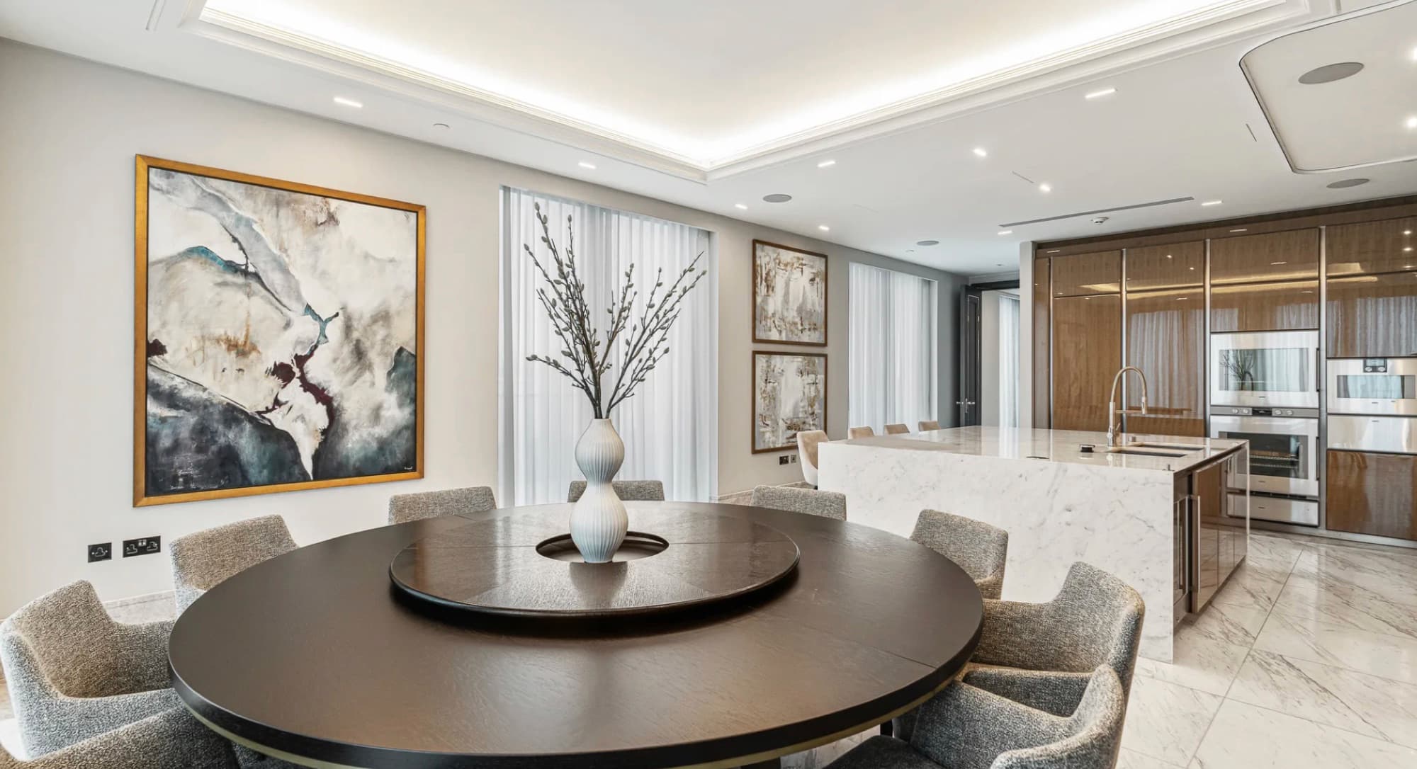 Formal drawing room with green velvet sofas and tall arched windows, services fully concealed within the ceiling design