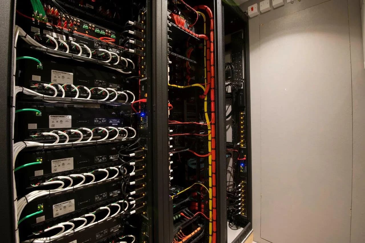 A Crestron equipment rack in a completed AVC project, with processors and amplifiers neatly stacked, every cable dressed, colour-coded and routed through vertical cable management