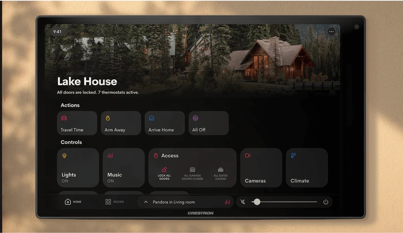 A wall-mounted Crestron touch screen showing the home view for a property, with one-touch actions for arriving and leaving above controls for lights, music, access, cameras and climate